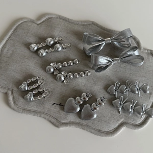 Vue détaillée de l'ensemble de barrettes argentées avec nœuds, cœurs et perles sur lin