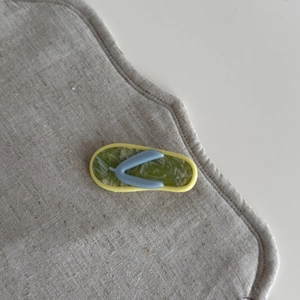 Detail view of a green marbled acetate hair clip shaped like a cute summer flip-flop sandal