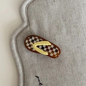 Detailed close-up of a flip-flop shaped hair clip with yellow straps and checkered pattern