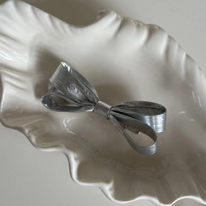 Détail de la barrette à cheveux nœud papillon argentée avec texture métallique douce