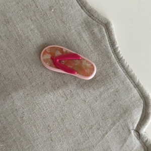 Detailed close-up of a flip-flop shaped tortoiseshell acetate hair clip on linen background