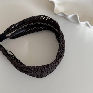 Détail d'un serre-tête tressé creux marron foncé avec motif résille et couche antidérapante