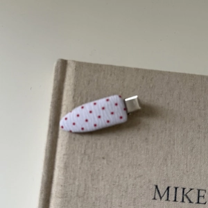 Close-up of white fabric hair clip with red polka dots on a silver metal duckbill base