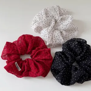 Three-piece satin polka dot scrunchie set in white, red, and black with brand woven label