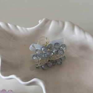 Close-up of light blue ribbon bow and grey crystal beads on a hair claw clip