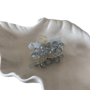 Elegant blue crystal beaded bow hair claw clip for women in a white ceramic dish