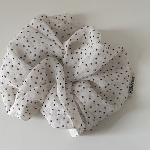 Detail of white satin scrunchie with black polka dots and sewn brand label on fabric