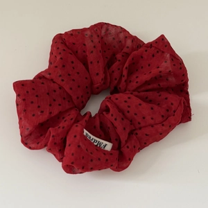 Detail of red satin scrunchie with black polka dots and white brand label