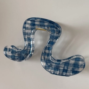 Detail of blue and white checkered wave hair claw clip with golden metal spring