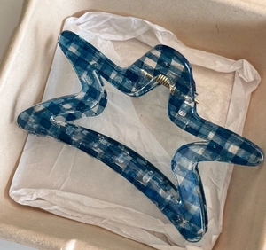 Detail of blue and white checkered star hair claw clip with transparent acetate finish