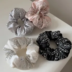 Vue détaillée de quatre chouchous de luxe en satin avec des strass et des perles décoratives