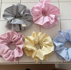Set of five handmade striped scrunchies in pastel colors on white tile surface
