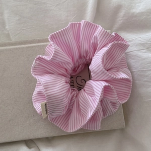 Chic pink and white striped scrunchie with Hand Made label on a textured book surface