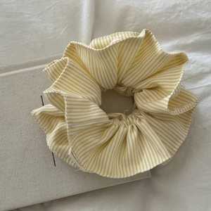Detailed close-up of yellow and white striped fabric scrunchie on a textured book