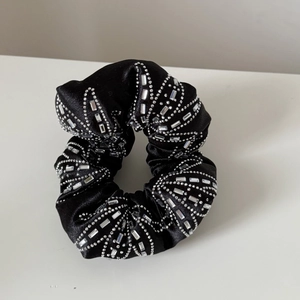 Gros plan d'un chouchou en satin noir orné de motifs élégants en strass brillants