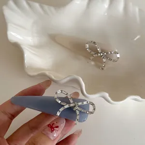 Elegant bow zircon hair clips in misty blue and creamy white on a shell tray