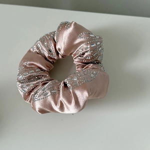 Détail d'un chouchou en satin rose orné de strass argentés brillants pour cheveux