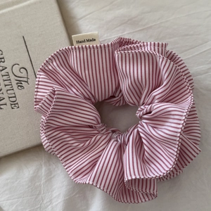 Detailed close-up of a red and white striped scrunchie with a Hand Made fabric label