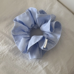 Detailed macro view of the blue and white striped fabric scrunchie with handmade tag
