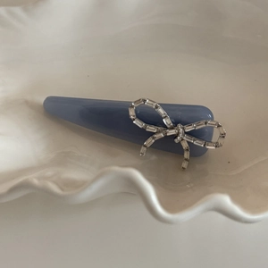 Detail shot of blue acrylic hair clip with shimmering zircon bow on a ceramic tray