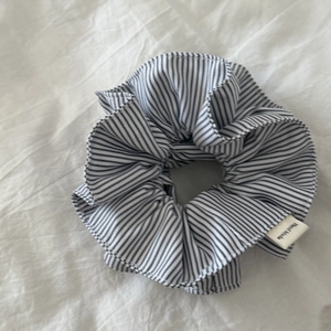 Detail of large black and white striped hair scrunchie with a handmade woven label tag