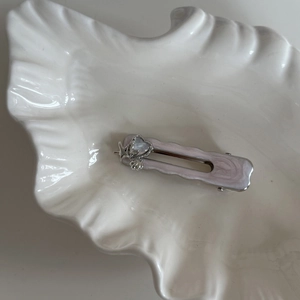 Close-up of pink marble starfish hair clip with heart rhinestone in a seashell dish
