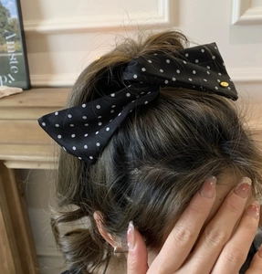 Close-up of black satin polka dot bow hair clip with gold metal buckle detail