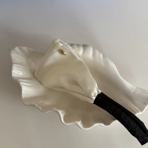 Detail of satin hair clip with cream fabric and elegant gold metal brand tag