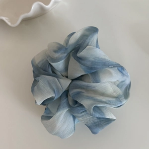 Detailaufnahme eines sternenblauen Scrunchie-Haargummis aus glänzendem Seidenstoff