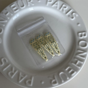 Three-piece set of yellow drop-shaped hair clips with blue polka dots in a ceramic tray