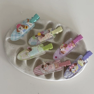 Gros plan de six barrettes chiots en acrylique coloré sur un plateau crème montrant les détails