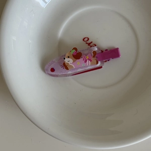 Détail d'une pince à cheveux violette en acrylique avec chien et motif fraise
