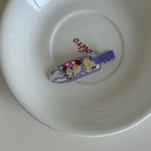 Vue détaillée d'une pince à cheveux violette motif chiot dessin animé sur assiette blanche