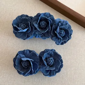 Set di fermagli a banana con rose in denim blu per coda di cavallo su sfondo beige