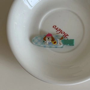 Détail d'une pince à cheveux pour enfant avec motif de petit chien et carreaux bleus