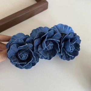 Dettaglio macro di un fermaglio per capelli con rosa in denim blu fatto a mano con texture