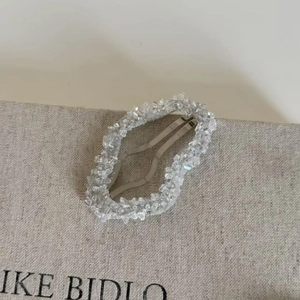 Gros plan détaillé d'une pince à cheveux en cristal bleu sur tissu gris texturé