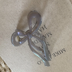 Close-up of a large ribbon bow hair claw clip in translucent smoke gray resin finish