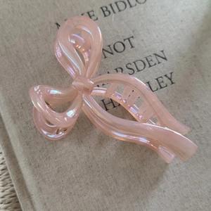 Macro view of pearlescent pink ribbon bow hair claw clip with shimmering texture
