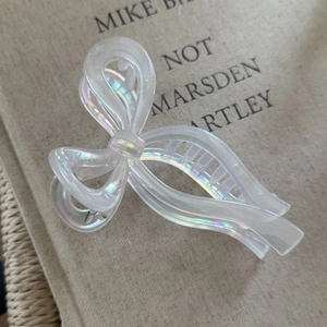 Macro view of pearlescent ribbon bow hair claw clip showing iridescent pearl texture