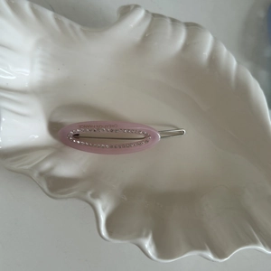 Détail d'une pince à cheveux ovale rose avec strass et lettrage Creation France