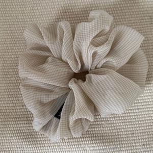 Close-up of semi-transparent beige gingham gauze scrunchie with refined texture
