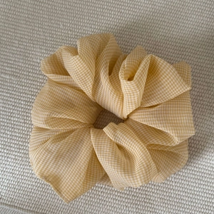 Elegant yellow gingham tulle scrunchie for women hair styling on woven fabric background
