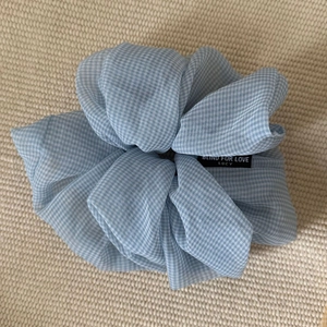 Light blue checkered scrunchie with sheer fabric and black woven label on beige knit