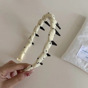 Close-up of the non-slip comb teeth on this cream polka dot braided headband