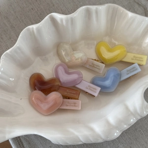 Elegant multi-colored heart-shaped acetate hair clips set in a white decorative shell bowl