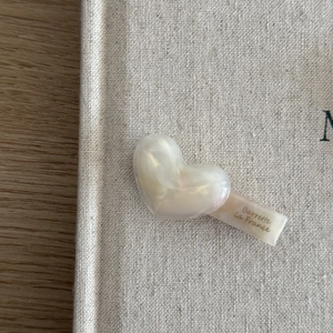 Close-up of heart-shaped pearlescent acetate hair clip with French lettering detail