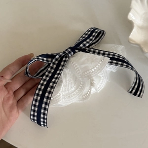 Détail de la barrette à cheveux à carreaux bleu marine avec dentelle blanche plissée
