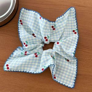 Détail d'un chouchou vichy bleu avec motifs cerises rouges et bords festonnés