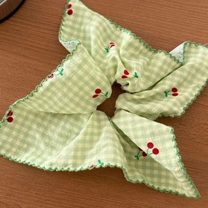 Détail du chouchou à carreaux avec motifs de cerises et bordure en dentelle verte